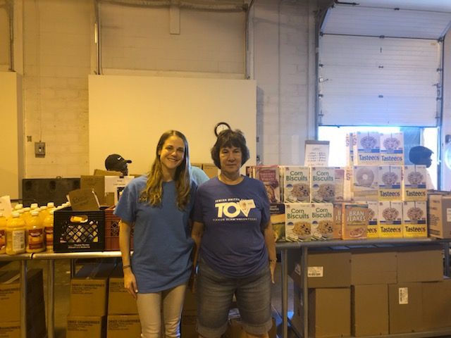 Heidi and Reenie stand in front of the cereal section at the JCC wearing blue t-shirts. 