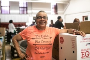 Mae stands beside a box of food at the Greater Galilee Baptist Church. 