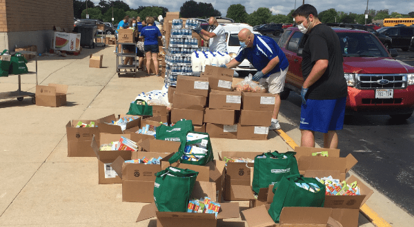 Teachers and volunteers pack boxes to go into cars at the Watertown Mobile Pantry