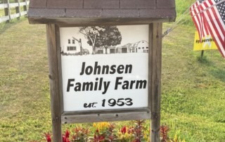 Johnsen Family Farm Sign with flowers underneath it.
