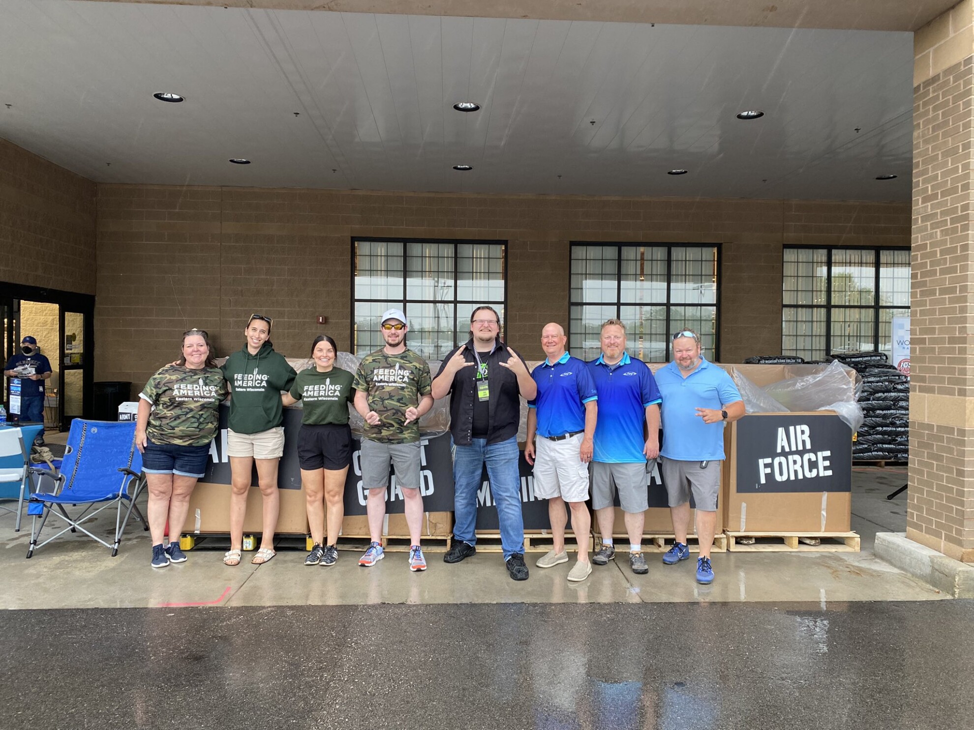 A group of volunteers, TDS employees, and Big Jake from Razor Wisconsin stand by donation boxes at Combat Hunger 2022. 